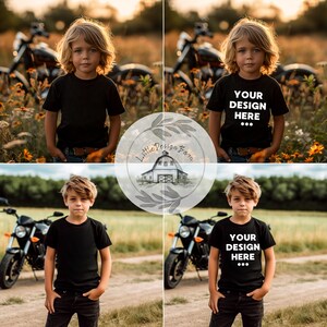 May include: A young person wearing a black t-shirt with the text "YOUR DESIGN HERE ***" printed on it. The person is standing in a field with a motorcycle in the background.