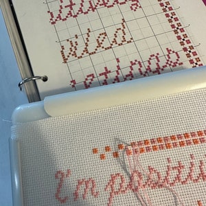 May include: A close-up of a cross-stitch project in progress. The project is a pink and orange cross-stitch design that reads "I'm pretty sure I'm a wizard".