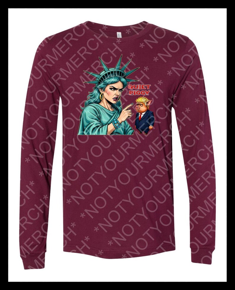 Peut inclure: T-shirt &agrave; manches longues bordeaux avec un dessin de la Statue de la Libert&eacute; pointant vers un cochon en costume, avec le texte "QUIET PIGGY". La Statue de la Libert&eacute; est repr&eacute;sent&eacute;e avec une peau turquoise et une couronne.