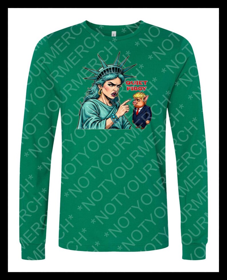 Peut inclure: T-shirt vert &agrave; manches longues avec un dessin de la Statue de la Libert&eacute; pointant vers un cochon en costume, avec le texte "QUIET PIGGY". Le t-shirt porte le texte "NOT YOUR MERCH" r&eacute;p&eacute;t&eacute;.