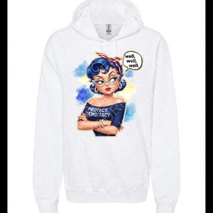 May include: White hoodie with a graphic of a woman with blue hair, glasses, and a red headband. The graphic includes the text "PROTECT DEMOCRACY" and speech bubbles saying "well, well, well."