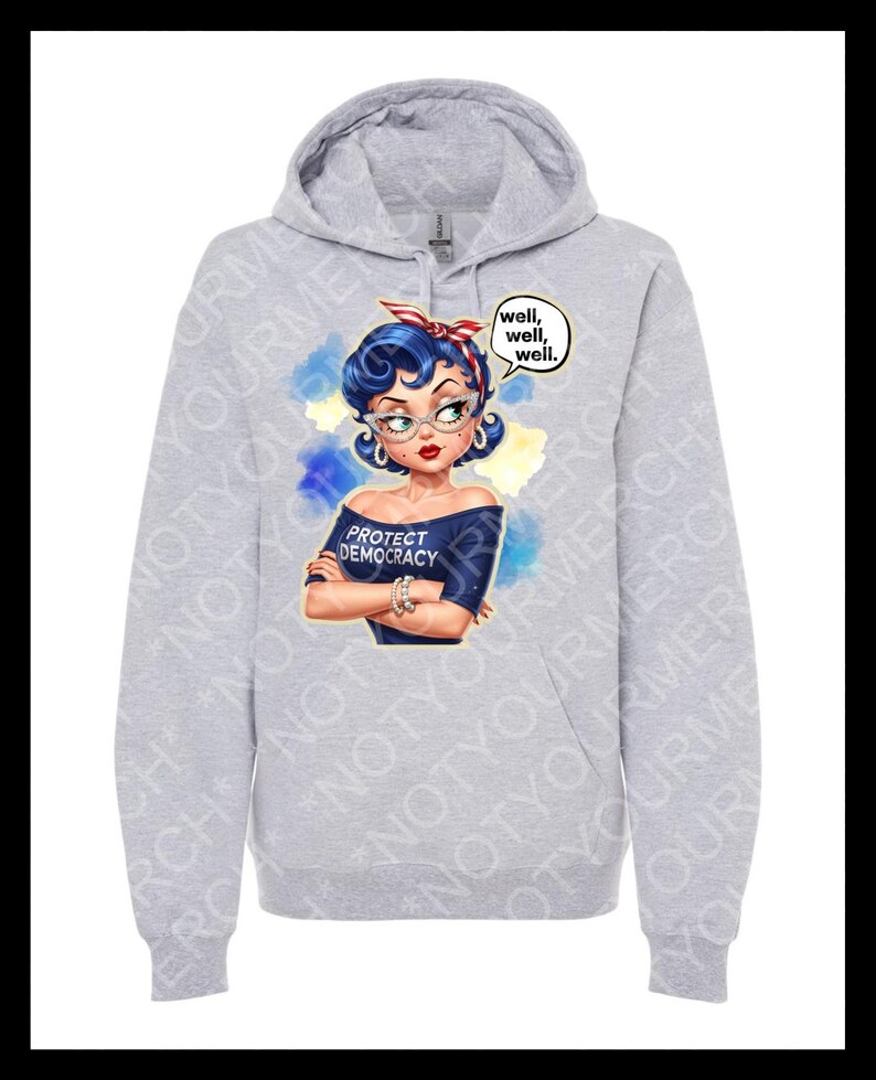 May include: A pale grey hoodie with a cartoon image of a woman with blue hair, glasses, and a red and white headband. The woman wears a blue off-the-shoulder top with the text "PROTECT DEMOCRACY." A speech bubble says "well, well, well."