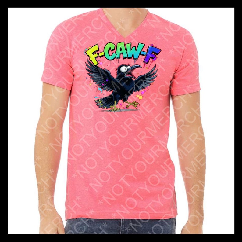 May include: A coral-colored V-neck t-shirt featuring a cartoon crow with outstretched wings and the text "F-CAW-F" in colorful graffiti-style lettering. The crow is black with yellow feet and a wide-open beak.