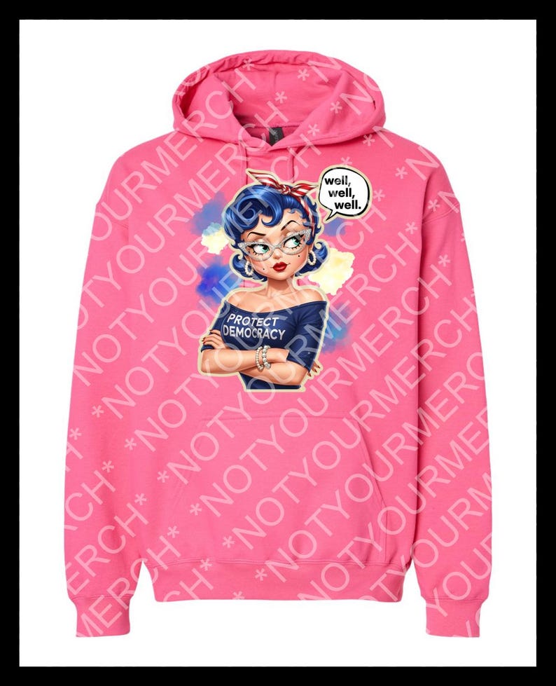 May include: Bright pink hoodie with a graphic of a woman with blue hair, glasses, and a red headband. The woman is wearing a blue shirt that says "PROTECT DEMOCRACY." A speech bubble says "well, well, well."