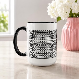 May include: A white ceramic mug with a black handle and interior, featuring a repeating black graphic pattern of horizontal lines and geometric shapes. The text "FUCK DONALD TRUMP" is vertically integrated into the design on the side of the mug.