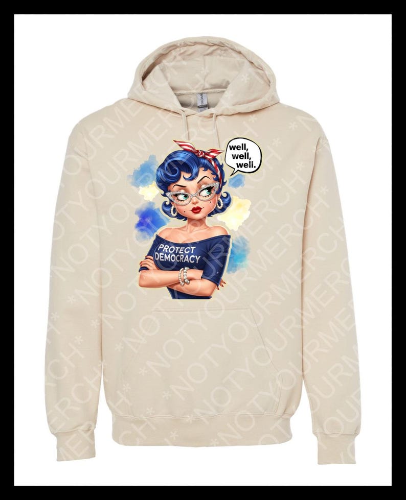 May include: A beige hoodie with a graphic of a woman with blue hair, glasses, and a red headband. The woman is wearing a blue off-the-shoulder top with the text "PROTECT DEMOCRACY." A speech bubble says "well, well, well."