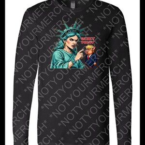Peut inclure: T-shirt noir &agrave; manches longues avec un dessin de la Statue de la Libert&eacute; pointant vers un cochon en costume. Le texte "QUIET PIGGY" est au-dessus du cochon. La Statue de la Libert&eacute; est turquoise, et le cochon porte un costume.