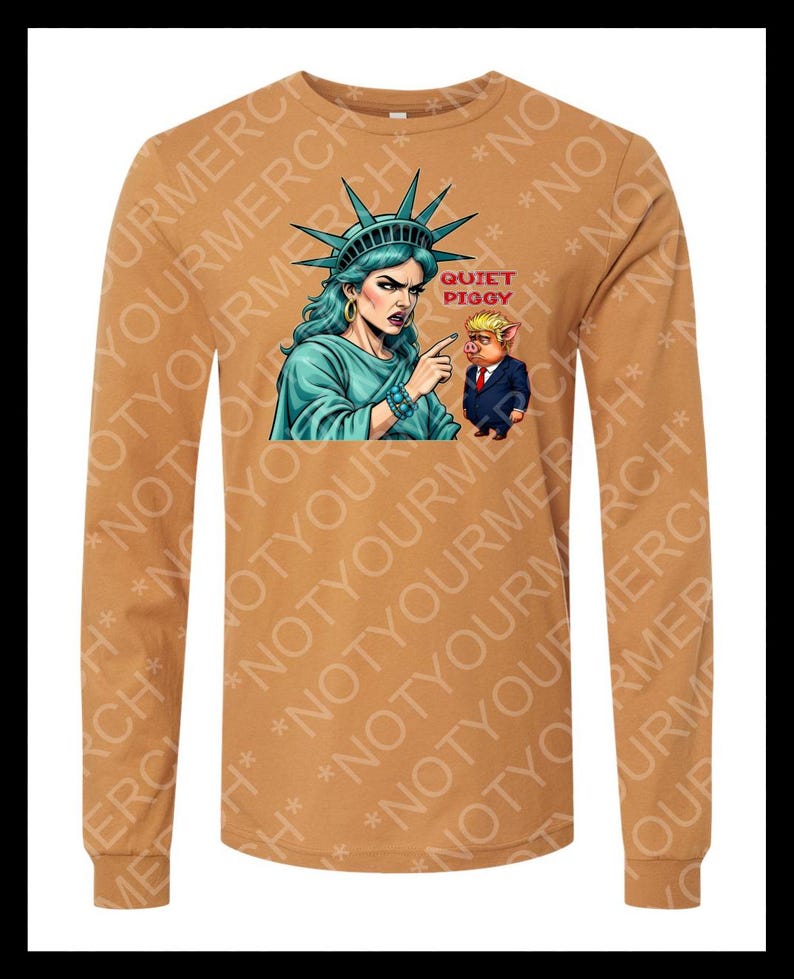 Peut inclure: Un t-shirt &agrave; manches longues de couleur beige avec un motif de la Statue de la Libert&eacute; pointant vers un cochon en costume. Le texte "QUIET PIGGY" est au-dessus du cochon. Le t-shirt porte l'inscription "NOT YOUR MERCH".