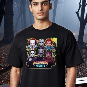 Könnte beinhalten: Schwarzes T-Shirt mit einem farbenfrohen Aufdruck von Horrorfilmfiguren, darunter Pennywise, Jason Voorhees und Freddy Krueger. Der Text "HALLOWEEN NIGHTS" wird unter den Figuren in einer Neon-Schriftart angezeigt.