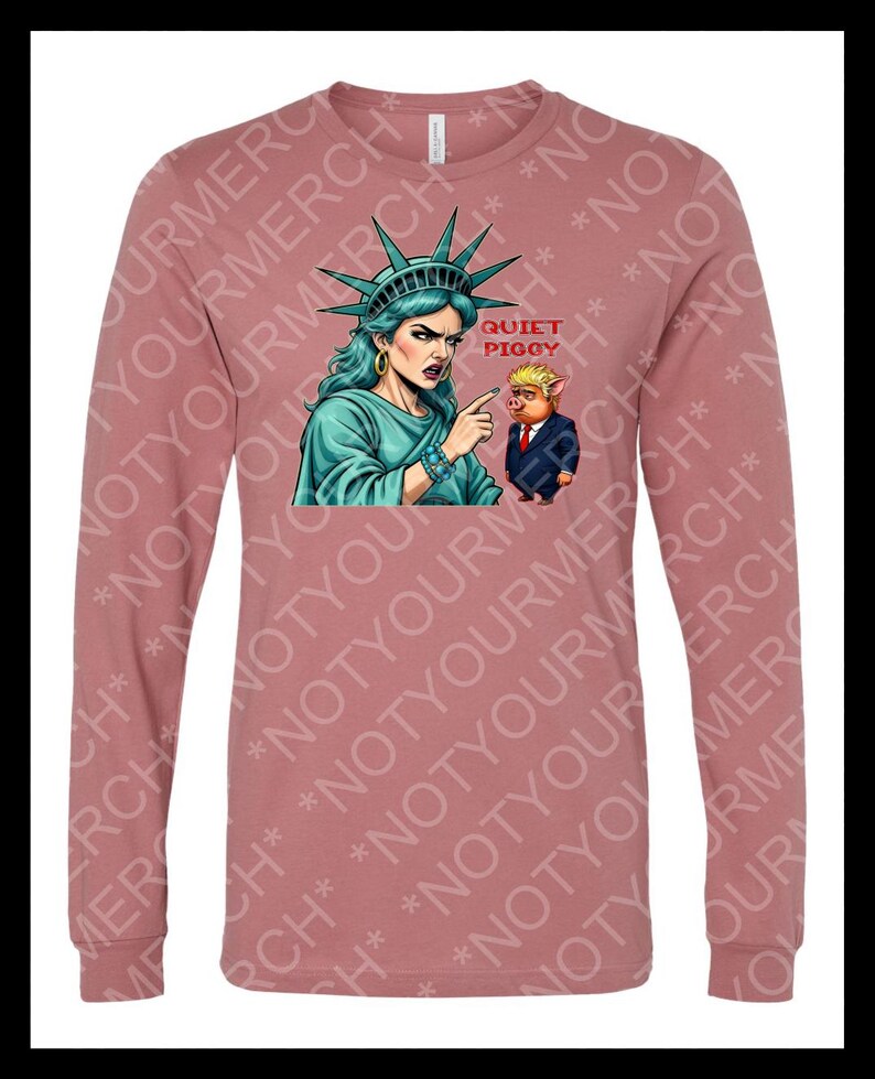 Peut inclure: T-shirt &agrave; manches longues de couleur mauve avec un motif de la Statue de la Libert&eacute; pointant vers un cochon en costume. Le texte "QUIET PIGGY" est au-dessus du cochon. Le t-shirt a un col rond et des manches longues.