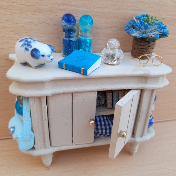 Dolls house miniature OOAK 'Shabby Chic' Distressed Side Cupboard Unit, flowers, Murano Ornaments, Porcelain Piggy Bank, Books, Bag, Glasses