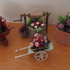 Miniaturowy domek dla lalek, różnorodne dekoracje ogrodowe w doniczkach, taczkach i studniach życzeń - róże, tulipany, liście i hortensje