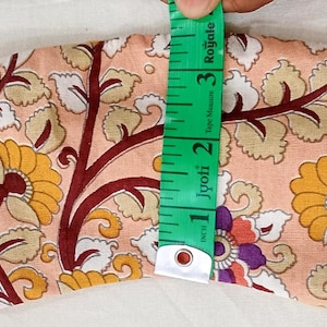 May include: A floral patterned eye mask in peach, yellow, and burgundy. The mask is approximately 3 inches (7.6 cm) wide and has an elastic band. The design features stylized flowers and leaves.