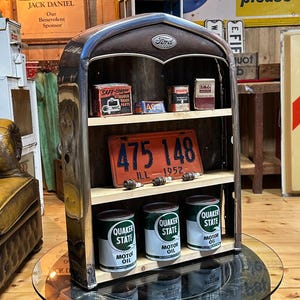 Op de afbeelding: Een vintage stijl plankeneenheid met een Ford-embleem. Het heeft houten planken met antieke motorolieblikken, bougies en een rode nummerplaat. De eenheid heeft een verchroomd frame en een donkerbruine bovenkant, wat een klassiek automotief thema oproept.