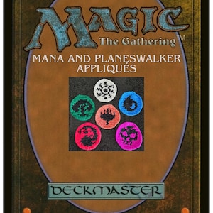Puede incluir: Una tarjeta Magic: The Gathering marrón y dorada con el texto "MAGIC The Gathering" y "Mana and Planeswalker Appliqués". La tarjeta presenta seis apliques de ganchillo coloridos con varios símbolos.