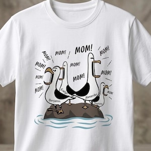 Peut inclure: T-shirt blanc avec une illustration de quatre mouettes sur un rocher, chacune criant "MOM!". Les noms des mouettes sont Benjamin, Evelyn, Alexander et Charlotte. Le design est en noir et blanc.