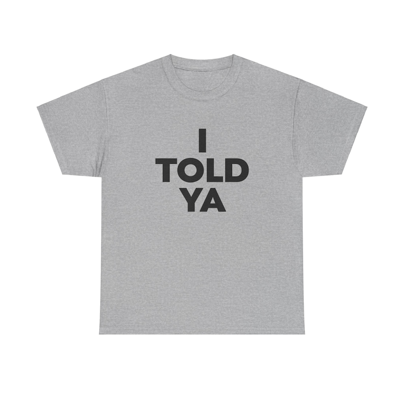 May include: A heather gray t-shirt with the text "I TOLD YA" printed in black.