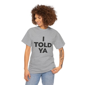 May include: A heather grey t-shirt with the text "I TOLD YA" printed in black.