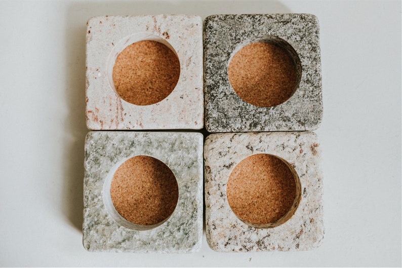 May include: Four square stone candle holders with cork inserts. Each holder has a different pattern of gray, white, and brown.