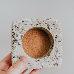 May include: A square, speckled, light gray granite coaster with a round, cork insert.