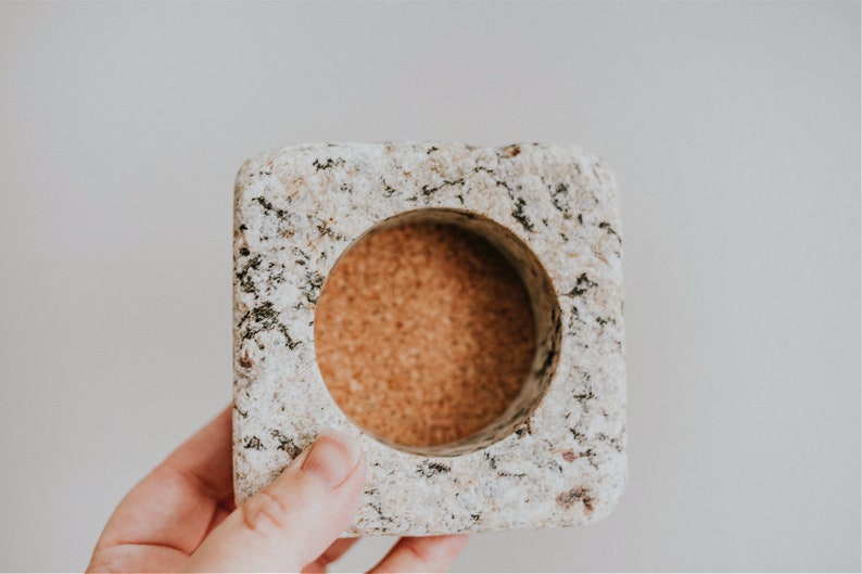 May include: A square, speckled, light gray granite coaster with a round, cork insert.