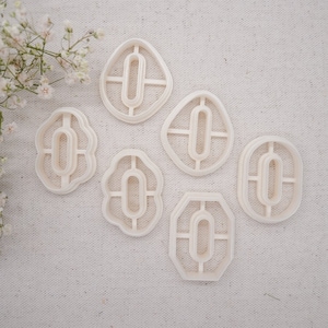 May include: Set of six white plastic cookie cutters shaped like different variations of the number zero.