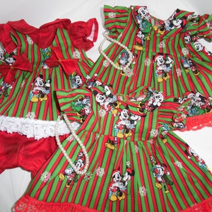 Puede incluir: Tres vestidos a rayas rojas y verdes con un tema navideño con Mickey Mouse y Minnie Mouse. Los vestidos tienen un borde de encaje blanco y están decorados con lazos rojos.