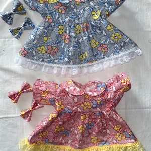May include: Two floral print dresses with lace trim. The top dress is blue with white lace and the bottom dress is red with yellow lace.