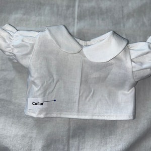 May include: White cotton doll shirt with a Peter Pan collar and short puffed sleeves. The shirt has the word "Collar" written on it.