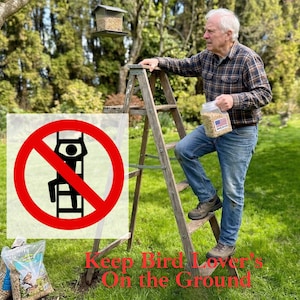 May include: A wooden stepladder with a red circular prohibition sign featuring a black icon of a person climbing a ladder. The text reads Keep Bird Lover's On the Ground. A clear plastic container of birdseed with a Made in USA flag label is held.