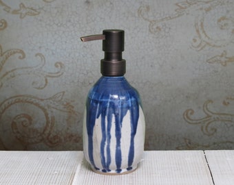 May include: A blue and white ceramic soap dispenser with a bronze pump. The dispenser has a drip glaze design.