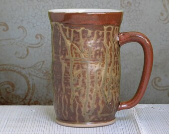 May include: A brown ceramic mug with a textured, mottled glaze. The mug has a large handle and a rounded base.