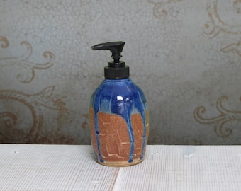 May include: A blue and brown ceramic soap dispenser with a black pump. The dispenser has a textured surface and a unique glaze.