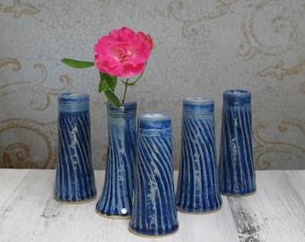 May include: Five small blue and white striped ceramic bud vases. One vase holds a single pink rose.