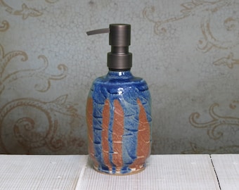 May include: A blue and brown ceramic soap dispenser with a metal pump. The dispenser has a unique, hand-painted design.
