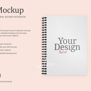 Op de afbeelding: Een witte spiraalgebonden notitieboek mockup met de tekst "Your Design here" in grijs en roze. Het notitieboek is op een lichtroze achtergrond.