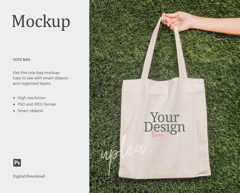 Pode incluir: Uma maquete de saco tote branco com o texto "Your Design here" impresso na frente. O saco &eacute; segurado por uma m&atilde;o contra um fundo de grama verde.