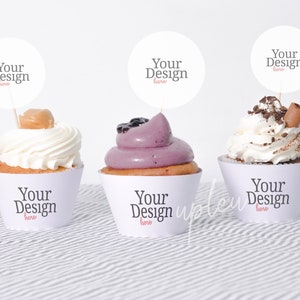 May include: Three cupcakes with different frostings and toppings. Each cupcake has a white paper liner with the text "Your Design here" printed on it. Each cupcake has a round white paper circle with the text "Your Design here" printed on it, attached to a toothpick.