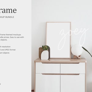 May include: A white frame mockup with a wooden frame, sitting on a white dresser with two drawers. A small potted plant and a white moon lamp are on the dresser. The text "zoey" is written in white on the wall behind the frame.