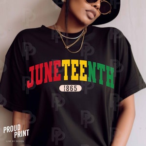 以下が含まれることがあります： 「Juneteenth 1865」の文字が弧状に書かれた黒いTシャツ。文字は赤、黄、緑で書かれている。