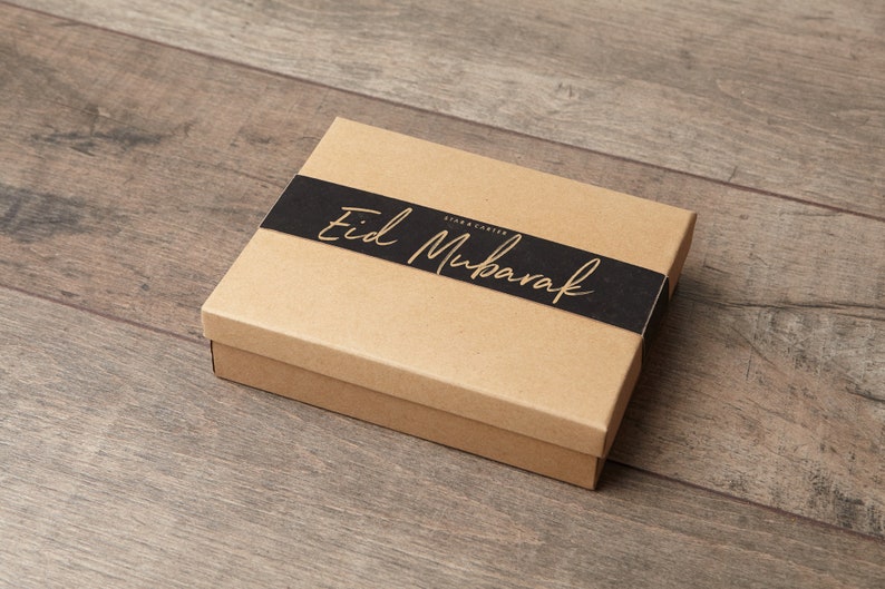 May include: A brown cardboard gift box with a black ribbon and the text "Eid Mubarak" in gold lettering.