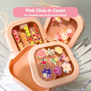 Op de afbeelding: Perzikroze Click-In Cases voor snuisterijen en kleine losse dingen! De vierkante cases hebben doorzichtige deksels. De cases zijn gevuld met kleurrijke stickers van bloemen en eten.