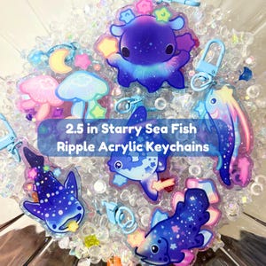 May include: A selection of 6.35 cm acrylic keychains showcasing sea creatures with a starry night theme. The keyrings feature a whale shark, octopus, and other fish, with a ripple effect design and attached key rings.
