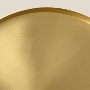 May include: A gold-colored metal tray with a smooth, brushed finish. The tray is round and has a slightly raised edge.
