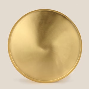May include: A round, gold-colored metal tray with a smooth, brushed finish.