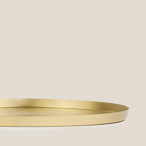 May include: A round, gold-colored metal tray with a smooth, slightly raised edge.