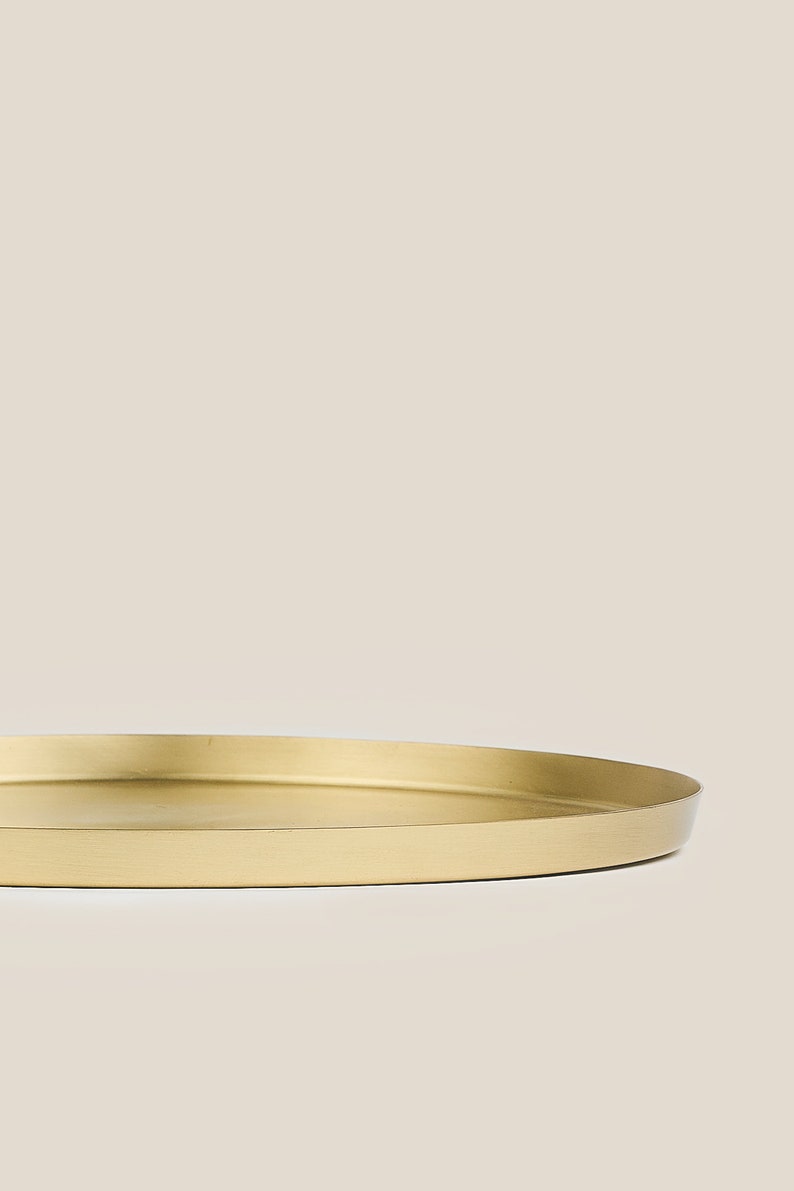 May include: A round, gold-colored metal tray with a smooth, slightly raised edge.
