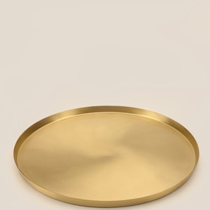 May include: A round, gold-colored metal serving tray with a smooth, slightly reflective surface.