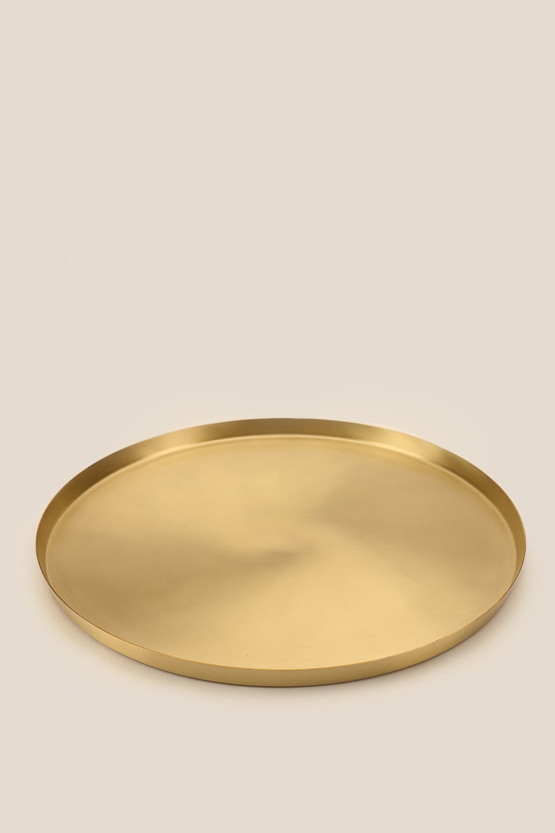 May include: A round, gold-colored metal serving tray with a smooth, slightly reflective surface.