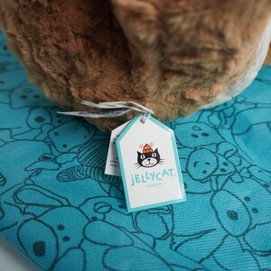 May include: A brown plush toy with a soft, textured surface resting on a bright turquoise fabric featuring a repeating black line-art pattern of various animals. A white tag with a black cat logo and the text JELLYCAT LONDON is attached.